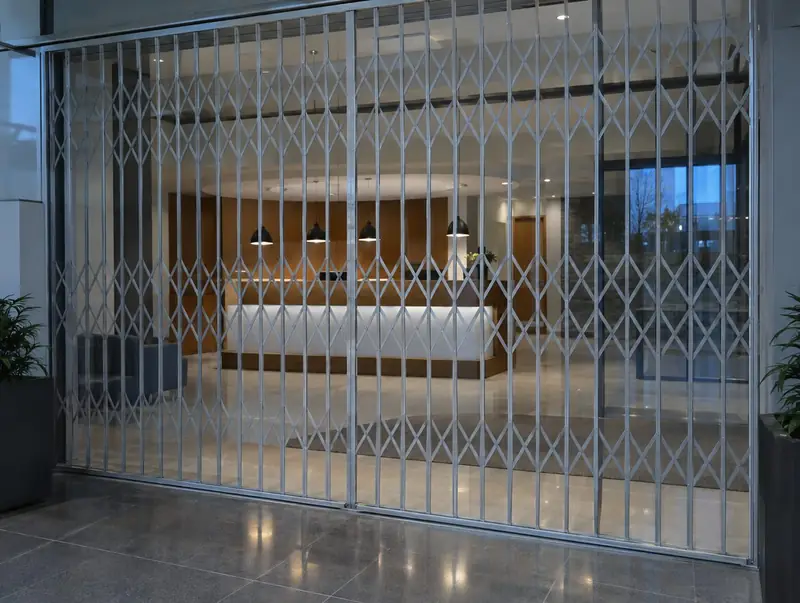 Silver retractable grille closed across the glazed entrance of an office reception